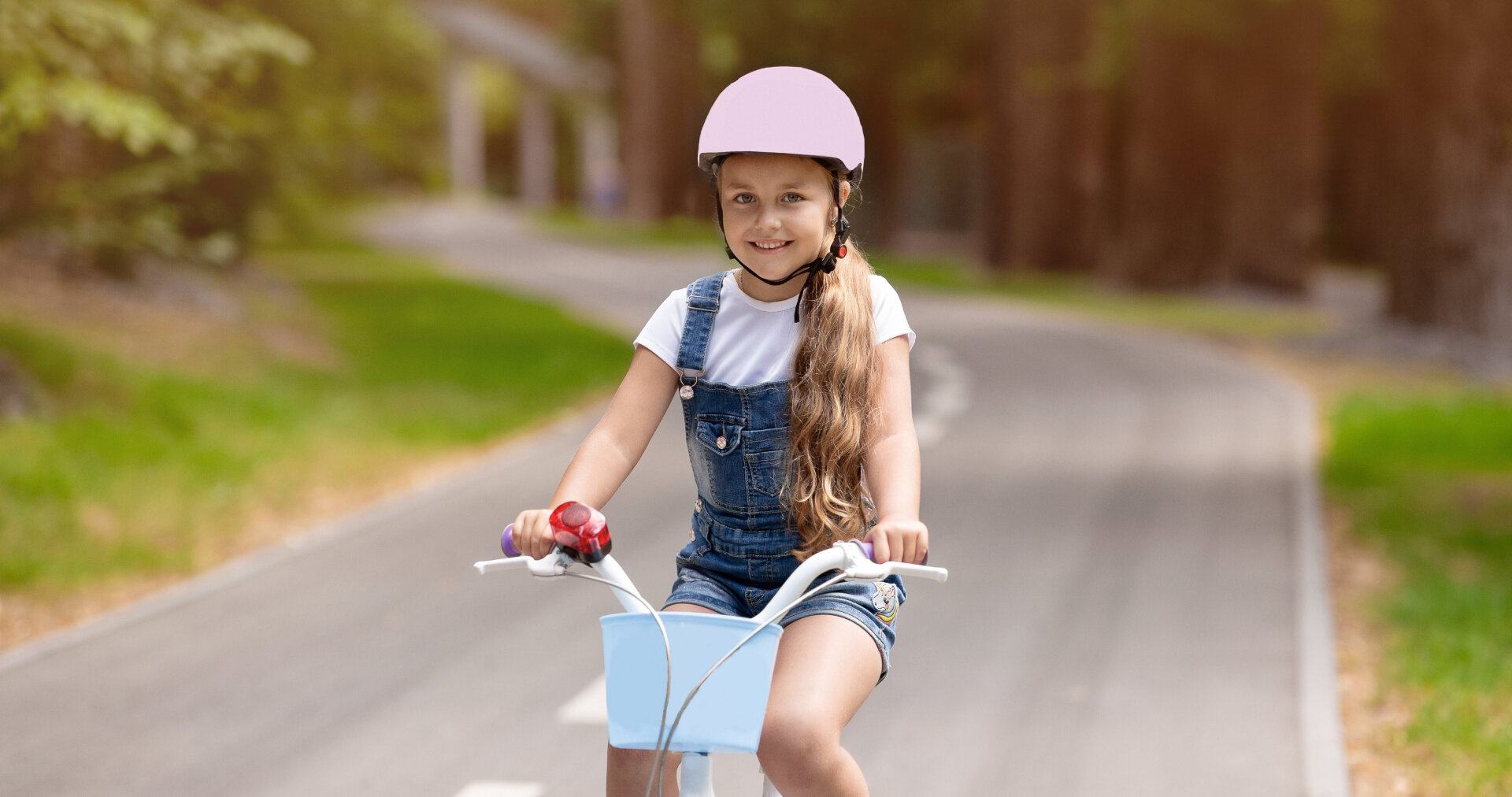 The young girl is smiling while riding her bicycle wearing pink helmet for safety purposes, (https://washington.wattelandyork.com/)