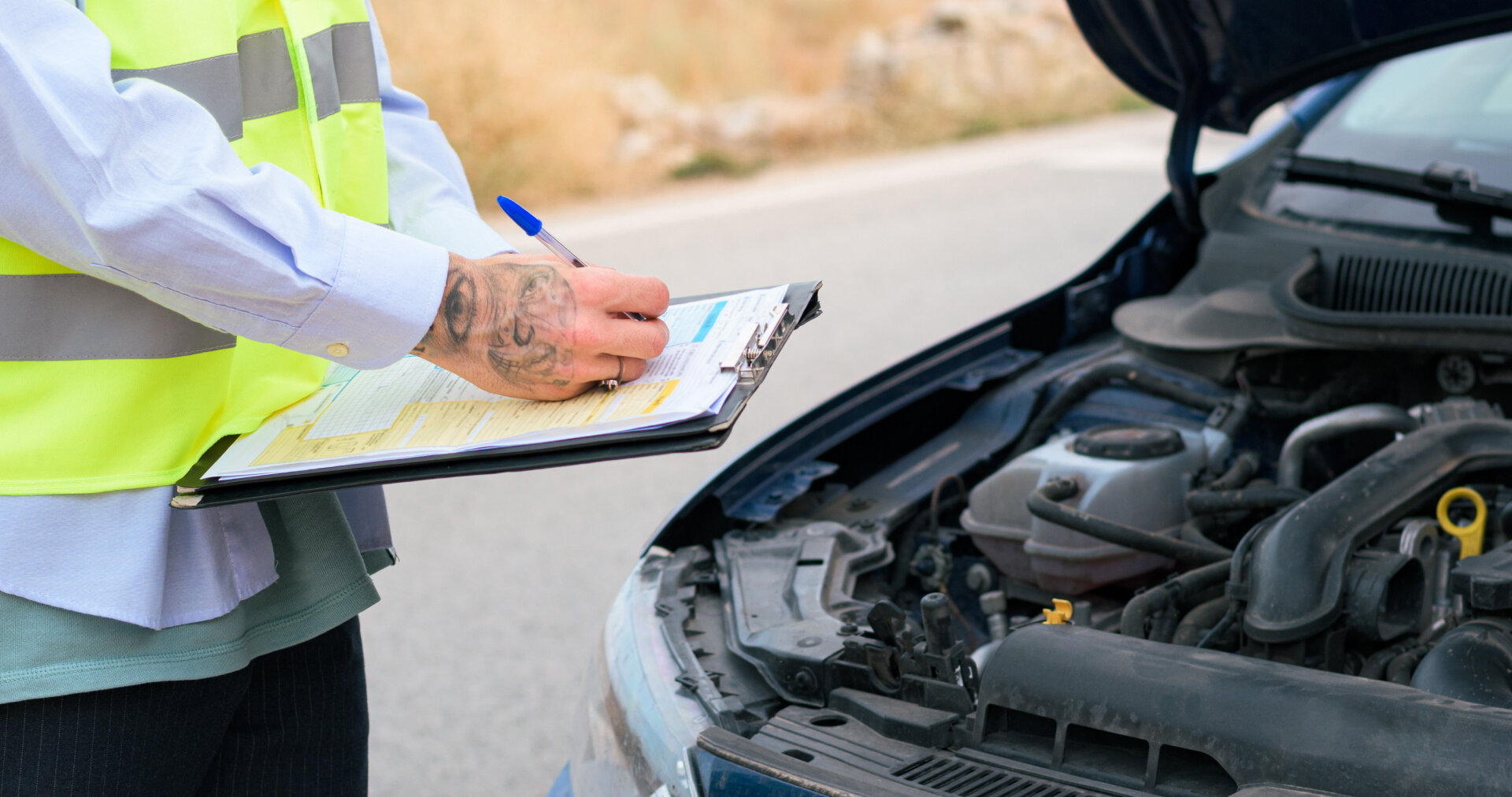 Man wearing a reflective vest signing a report of a car accident